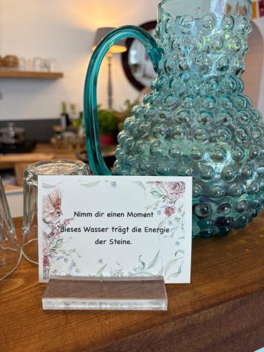 Ein dekoratives Glasgefäß und eine Karte mit einer Einladung zum Wasserglas.